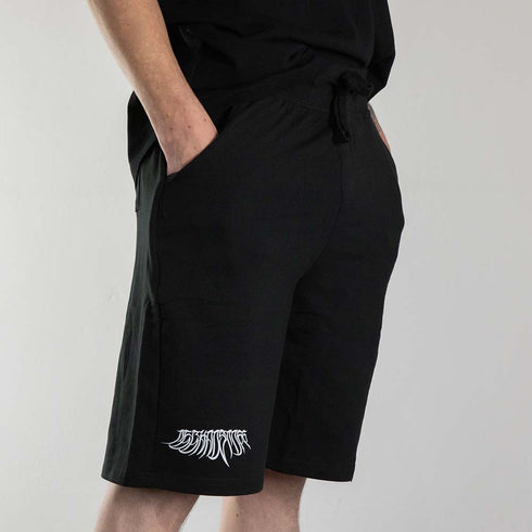 schwarze "Decay" kurze Hose, getragen von einem Mann, seitlich fotografiert
